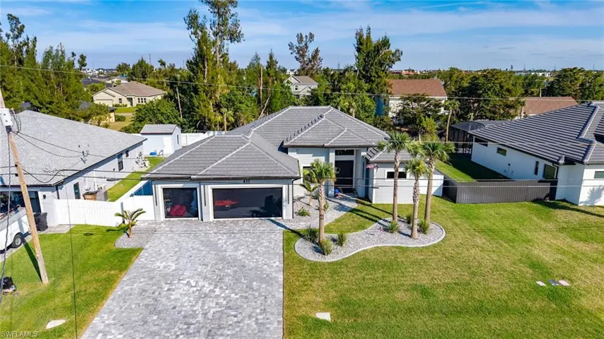 Ranch-style home featuring a garage, a residential view, decorative driveway, and a front yard