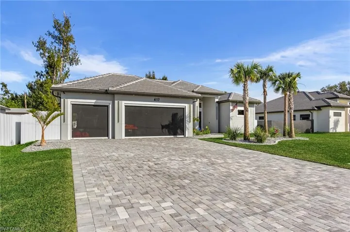 View of front facade with decorative driveway, an attached garage, fence, and a front yard