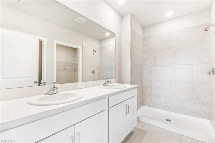 Bathroom with a walk in closet and a stall shower