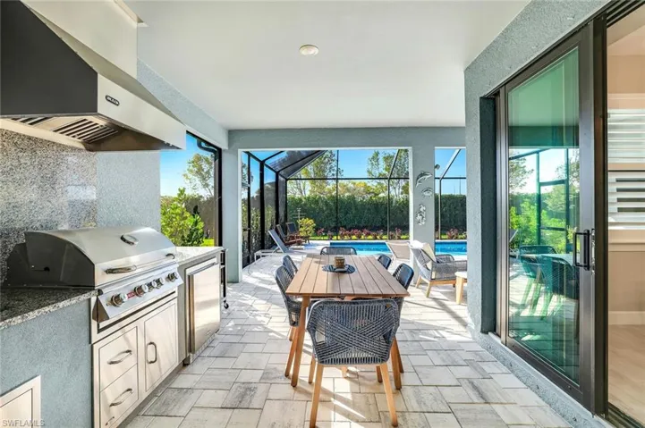 View of patio with an outdoor pool, outdoor kitchen / dining area, and a lanai
