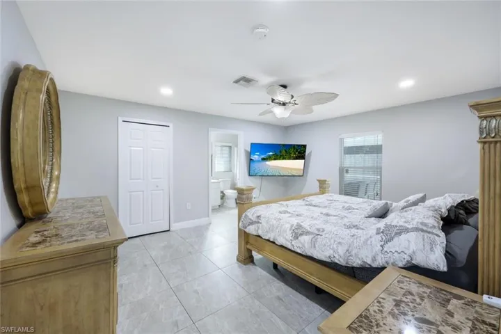 Tiled bedroom with a closet, ceiling fan, and ensuite bathroom
