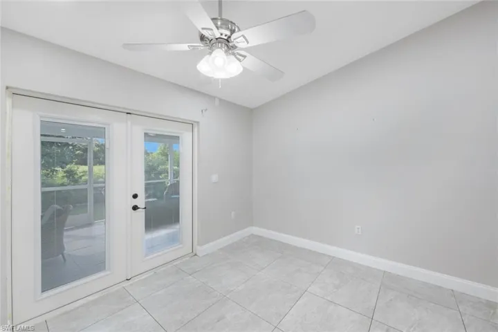 Tiled empty room featuring ceiling fan and french doors