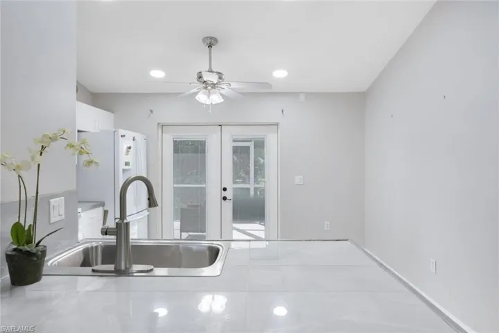 Kitchen featuring french doors, sink, ceiling fan, white refrigerator, and white cabinets