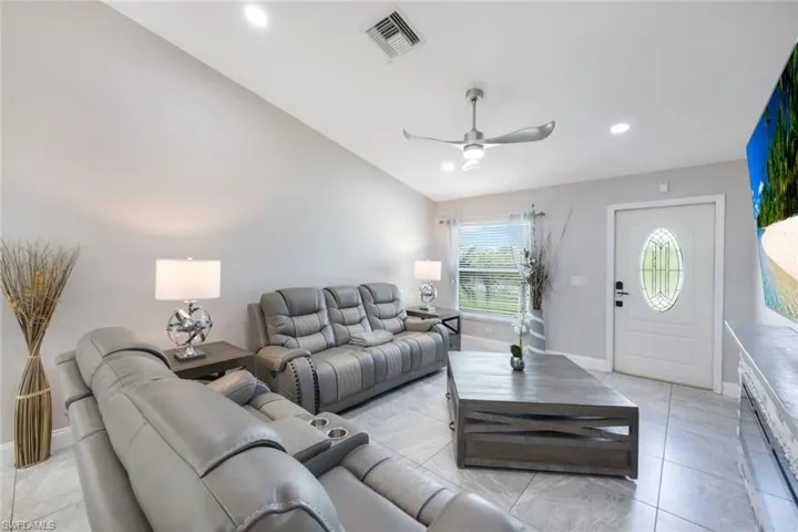 Living room featuring lofted ceiling, light tile patterned flooring, and ceiling fan