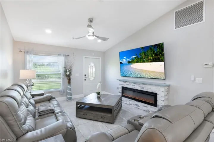 Living room with lofted ceiling, ceiling fan, and a fireplace