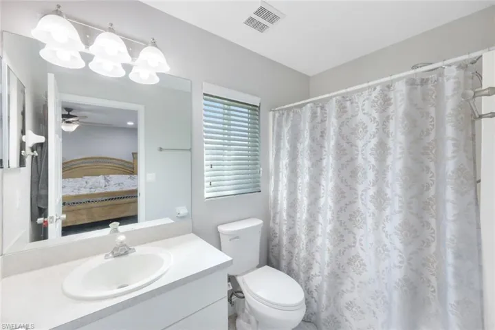 Bathroom featuring vanity, toilet, and ceiling fan