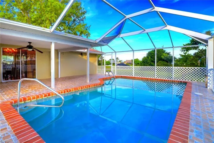Outdoor pool with glass enclosure, a sunroom, and a patio area