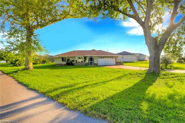 Ranch-style house with a front lawn, driveway, an attached garage, and stucco siding
