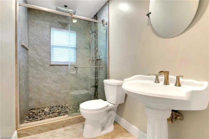 Full bath featuring a marble finish shower and toilet