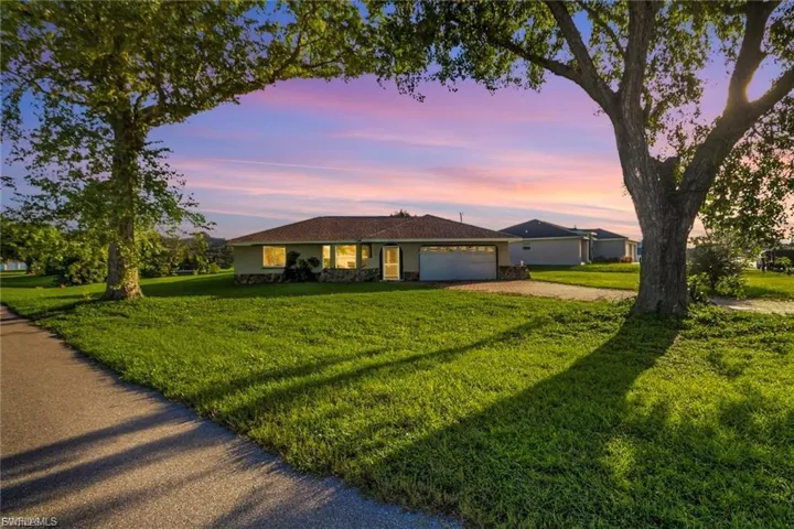 Ranch-style home featuring driveway, a yard, and a garage