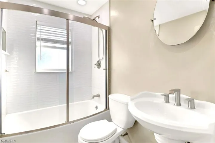 Bathroom with shower / bath combination with glass door and toilet