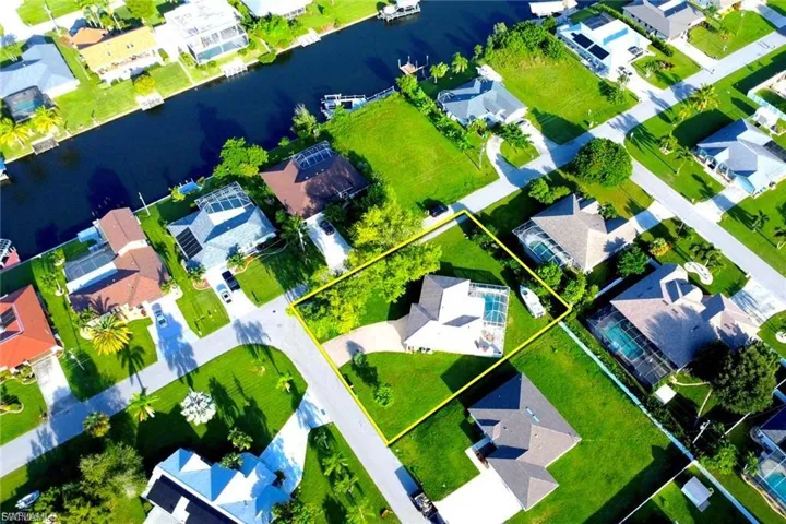 Aerial perspective of suburban area with property boundaries highlighted and a nearby body of water