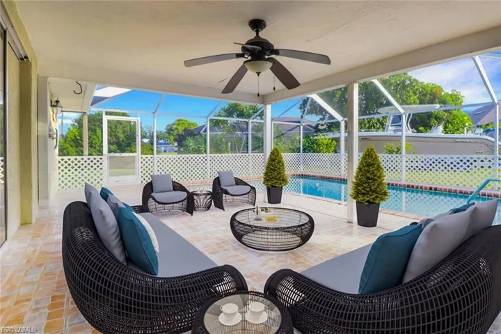 View of patio with outdoor lounge area, glass enclosure, a ceiling fan, a sunroom, and an outdoor pool