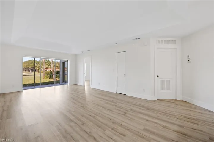 Unfurnished living room featuring visible vents, light wood-style flooring, and a tray ceiling
