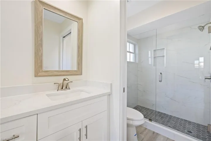 Full bath featuring toilet, a marble finish shower, and vanity