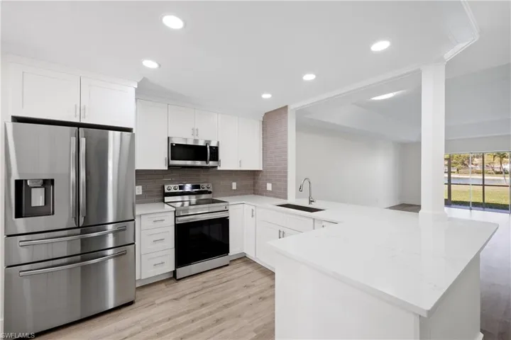 Kitchen with stainless steel appliances, light wood finished floors, a peninsula, and a sink