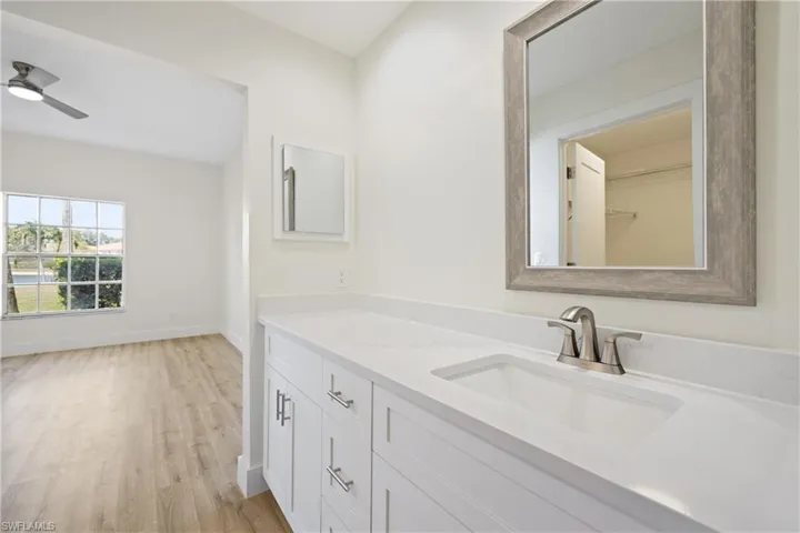 Bathroom featuring baseboards, wood finished floors, a ceiling fan, and vanity