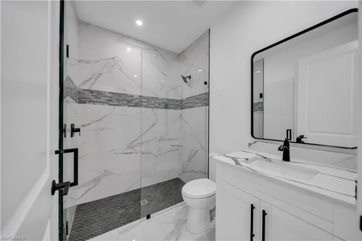 Full bathroom with a marble finish shower, vanity, marble look tiles, and recessed lighting