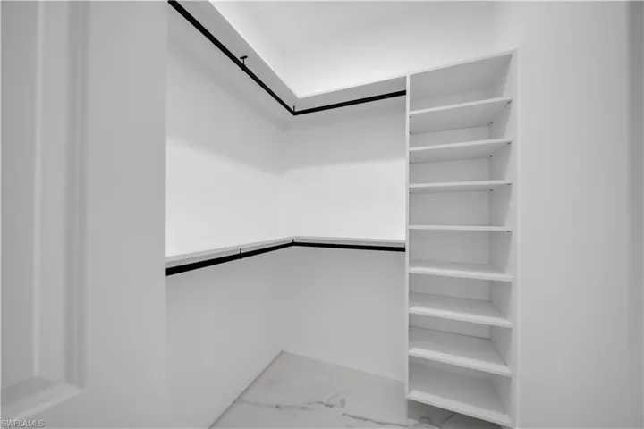 Walk in closet featuring light marble finish flooring