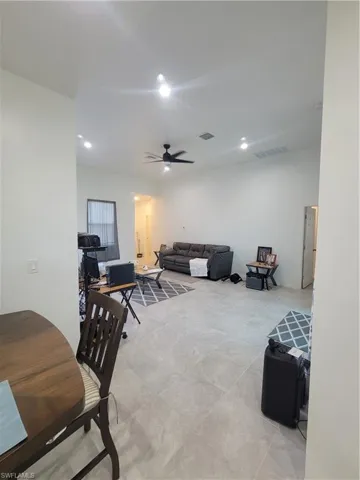 Living room with ceiling fan, french doors, light tile patterned floors, and a high ceiling