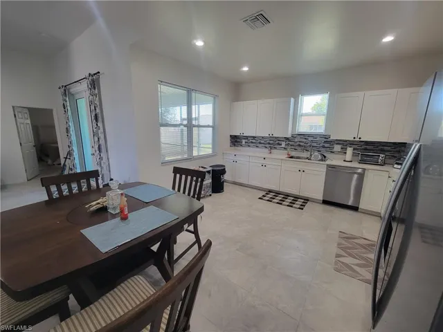 Kitchen featuring tasteful backsplash, dishwasher, white cabinets, and sink