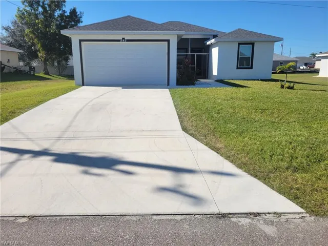 View of front of property featuring a front lawn and a garage
