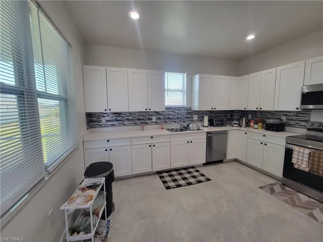 Kitchen with white cabinets, stainless steel appliances, and tasteful backsplash
