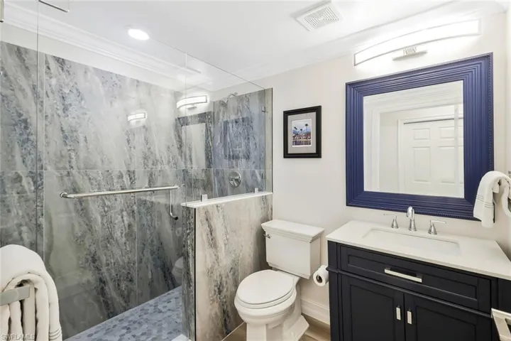 Full bath featuring vanity, crown molding, and a marble finish shower