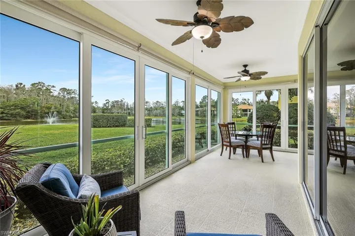 Sunroom with a ceiling fan and a water view