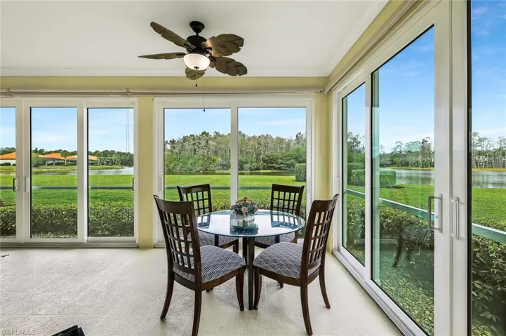 Sunroom / solarium with a water view, view of wooded area, and crown molding
