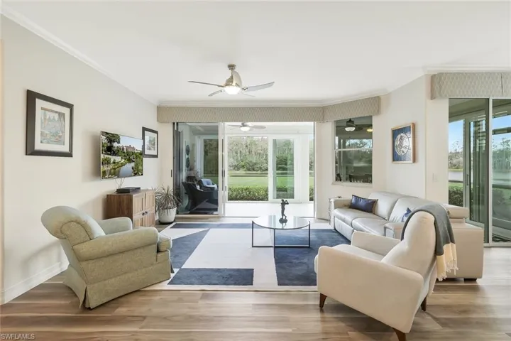 Living room featuring crown molding, wood finished floors, and ceiling fan