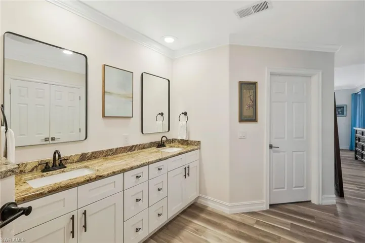 Full bathroom with double vanity, crown molding, and light wood-style floors