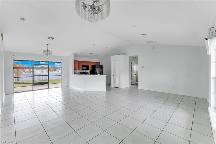 Unfurnished living room featuring light tile patterned flooring, suspended lighting, and a high ceiling