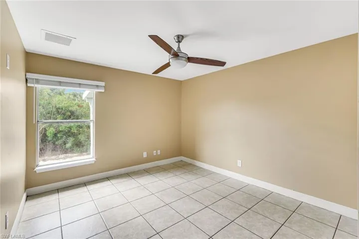 Empty room with ceiling fan and light tile patterned flooring