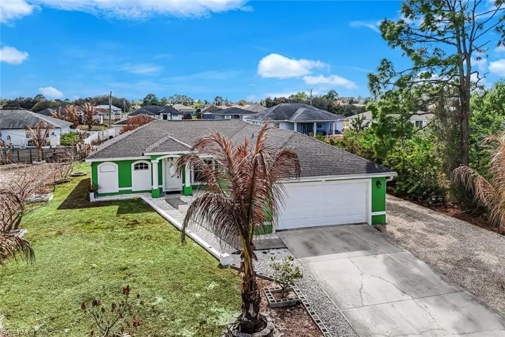 View of front of house with driveway, a front lawn, a residential view, a garage, and stucco siding