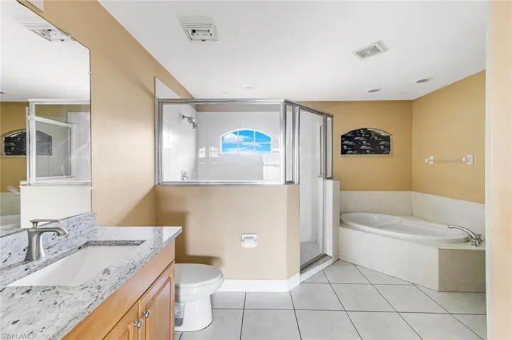 Bathroom featuring a bath, vanity, light tile patterned floors, and a stall shower