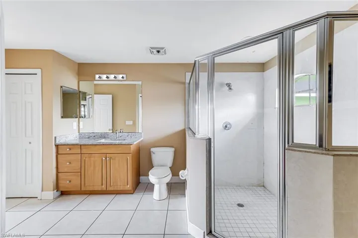 Full bath with a shower stall, vanity, light tile patterned floors, and a closet