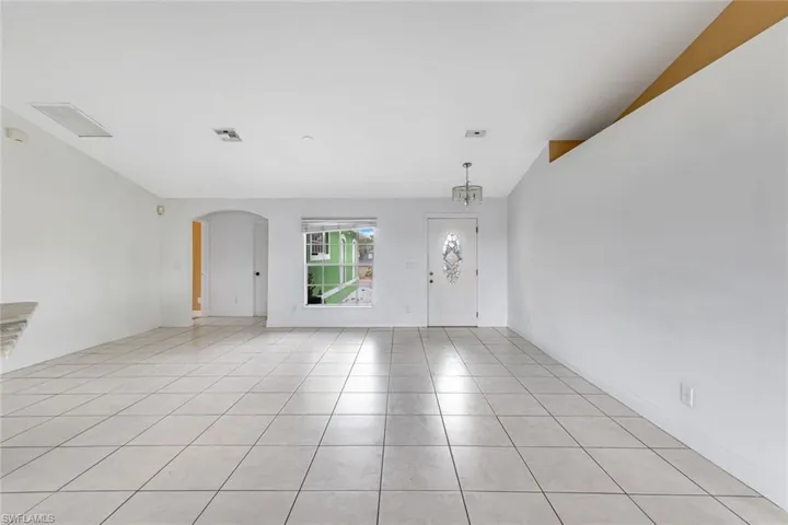 Entrance foyer with arched walkways, lofted ceiling, and light tile patterned flooring