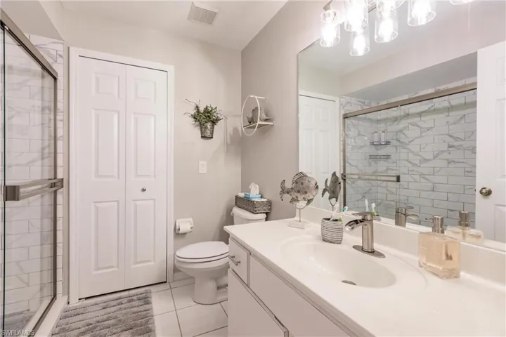 Bathroom with tile patterned floors, vanity, a shower with door, and toilet