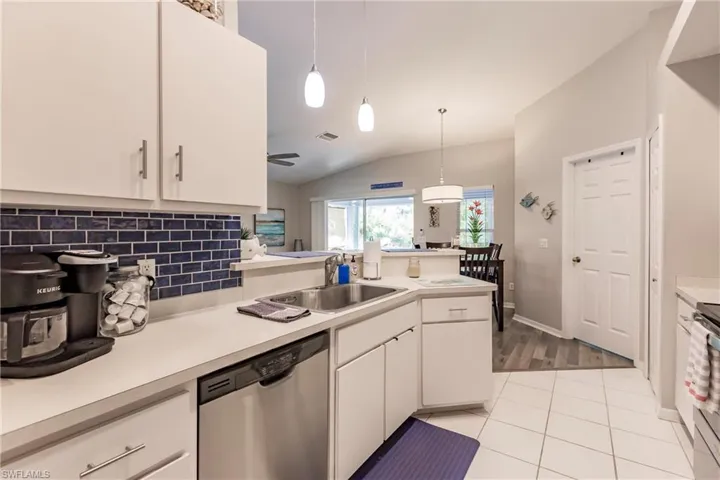Kitchen featuring white cabinetry, light wood-type flooring, appliances with stainless steel finishes, vaulted ceiling, and sink