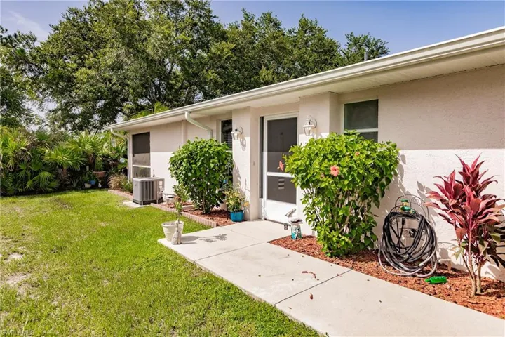 Entrance to property with central air condition unit and a yard