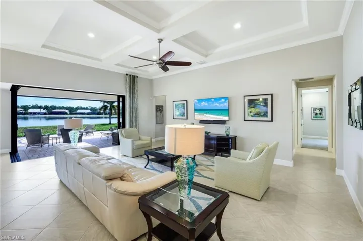 Living room featuring ceiling fan, crown molding, coffered ceiling, recessed lighting, and light tile patterned flooring