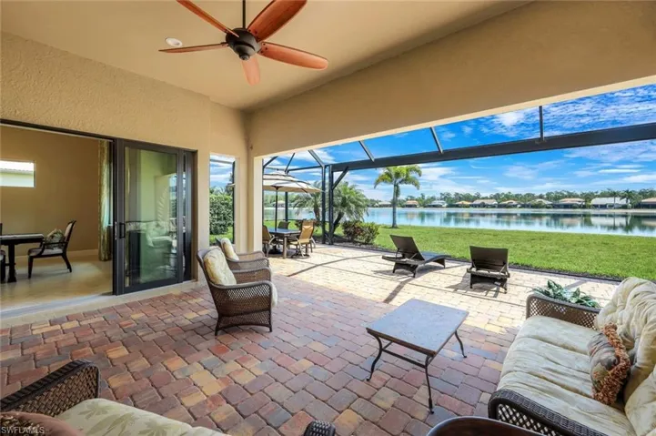 View of patio / terrace with a sunroom, outdoor dining area, ceiling fan, a lanai, and a water view