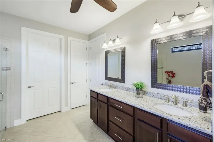 Bathroom with double vanity, a shower stall, separate bath tub, ceiling fan, and light tile patterned floors