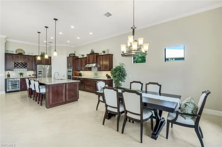 Dining area featuring crown molding, wine cooler, and hanging lights