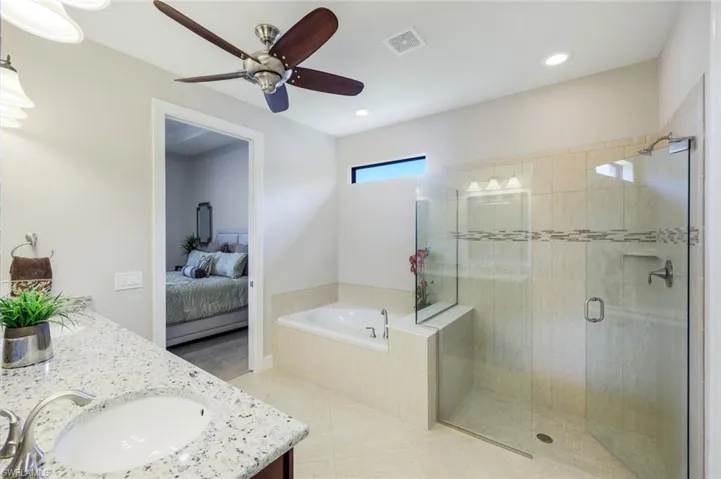 Full bath with double vanity, ensuite bath, light tile patterned flooring, a shower stall, and a separate bath