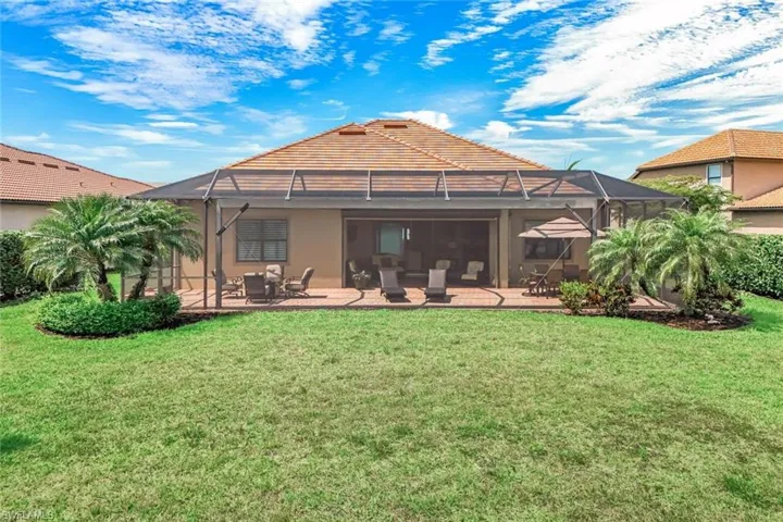 Back of house with glass enclosure, stucco siding, a yard, and a patio