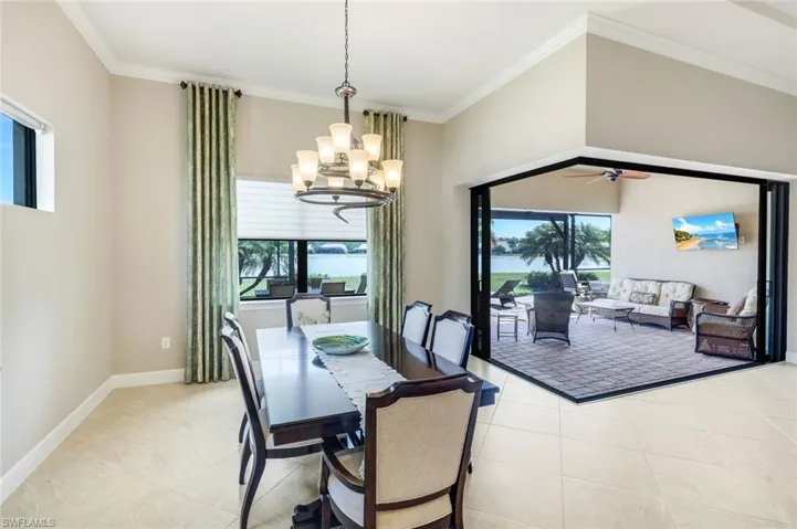 Dining space featuring crown molding, zero corner sliding glass doors, a chandelier, healthy amount of natural light, ceiling fan, and light tile patterned floors