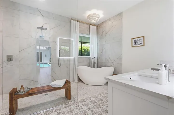 Spacious bathroom featuring a frameless glass shower enclosure, freestanding soaking tub, and a vanity with an integrated sink