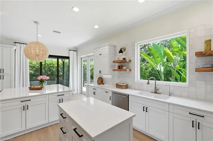 Bright kitchen featuring two islands with white countertops, recessed lighting, and light wood-finish flooring